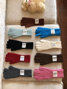 Guantes tácticos de lana de varios colores mostrados sobre un cojín beige suave