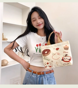 Detail view of cream canvas handbag with brown straps and cute colorful cartoon prints