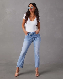 Dettaglio di jeans dritti a vita alta azzurri con design asimmetrico in vita