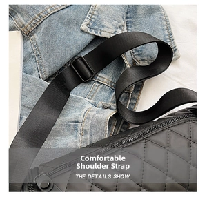 Detail of adjustable nylon shoulder strap on black quilted cylinder bag