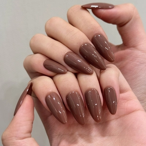 Dettaglio unghie finte a mandorla marrone cioccolato lucido con finitura mocha e trama liscia