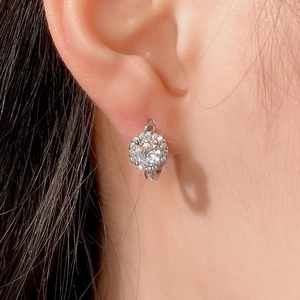 Close-up of sparkling round zircon halo hoop earrings worn on a woman's earlobe