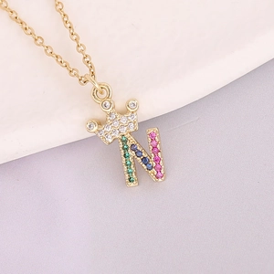 Macro shot of 18K gold crown necklace with colorful zircon letter N pendant