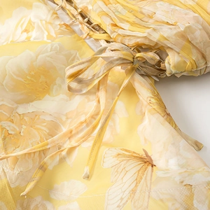 Detail of yellow floral dress showing chiffon fabric pleats and a drawstring bow tie
