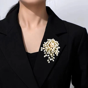Detail of a handmade pearl flower brooch pinned on a black suit lapel for women