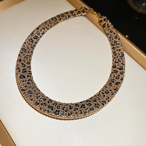 Detail view of leopard print choker necklace with gold metal clasp in a jewelry box
