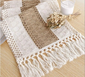 Detail of woven cotton linen table runner with fringes on a rustic wooden table surface