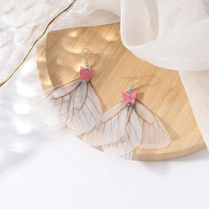 Elegantes pendientes de mariposa rosa con borlas de alas traslúcidas en bandeja de madera