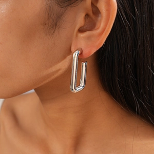 Side view of a model wearing a minimalist silver metallic rectangular U-shaped earring
