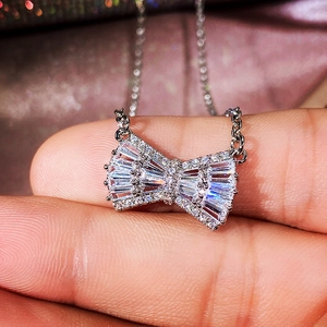 Macro shot of silver bow pendant necklace with sparkling cubic zirconia on chain