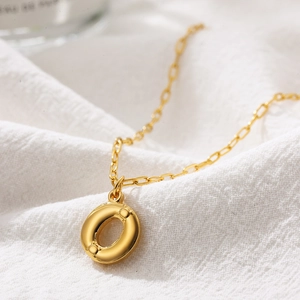 Detailed macro view of golden bubble letter O pendant with fine textured dot finish