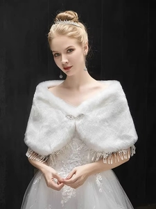 Detail of white faux fur bridal shawl featuring sparkling brooch and tassel decorations