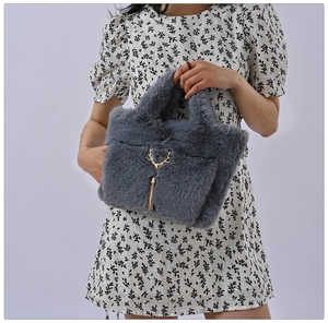Detail of grey faux fur handbag featuring gold reindeer charm and tassel accent