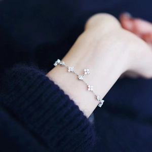 Close-up of 925 silver 18K gold clover bracelet with clear stones on model wrist