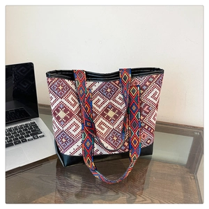 Ethnic geometric pattern tote bag with leather bottom trim on a desk with a laptop