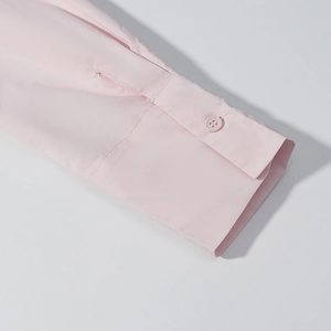 Détail du poignet d'une chemise rose clair avec coutures soignées et bouton transparent