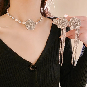 Détails d'un collier de fleurs argentées et de boucles d'oreilles à pompons avec cristaux