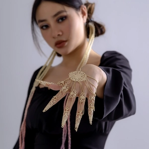 Detailed close-up of golden hollowed nail covers and filigree chain bracelet
