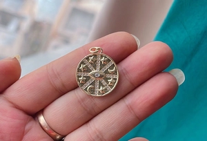 Detailed close-up of golden celestial charm with star, moon and evil eye motifs