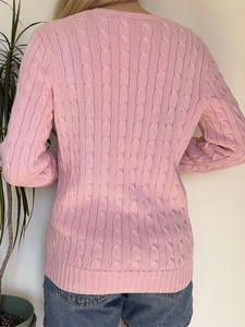 Détail d'un pull en maille torsadée rose montrant la texture douce et le tissage précis
