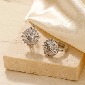 Detailed macro shot of sunflower stud earrings with cubic zirconia on stone and silk