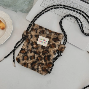 Détail d'un sac bandoulière en peluche léopard avec bandoulière corde sur table