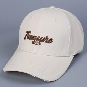 Detail of 3D letter embroidery and distressed brim on a beige cotton baseball cap