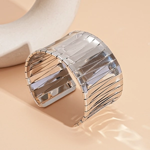 Detailed view of the wide silver metallic irregular open bangle with a polished finish