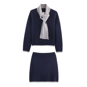Dettaglio del maglione in maglia blu scuro con sciarpa grigia e bordo gonna