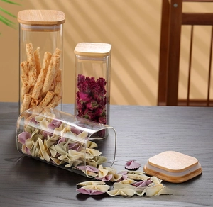 Detailed close-up of square glass storage jars with airtight bamboo lids on a wooden desk