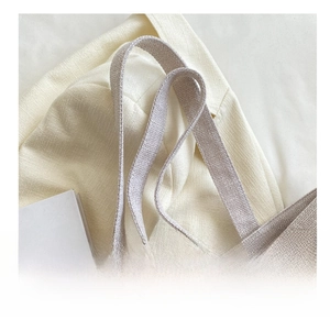 Detail of a woven shoulder strap on a cream tote bag with elegant texture focus
