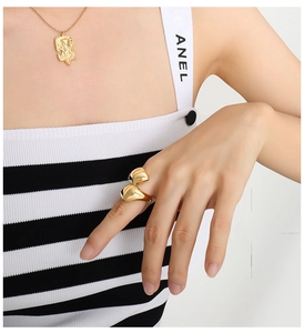 Detail of 18K gold plated titanium ring with a unique fluid design worn on model finger