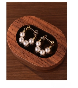 Detailed macro view of S925 sterling silver beaded pearl earrings in a dark wooden box