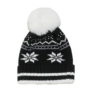 Detailed close-up of winter knit beanie showing snowflake pattern and fluffy pompom