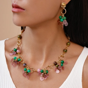 Bohemian gold necklace and earring set with green and pink beads on a female model