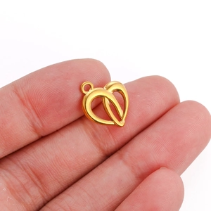 Macro shot of small golden double heart charms in stainless steel held between fingers