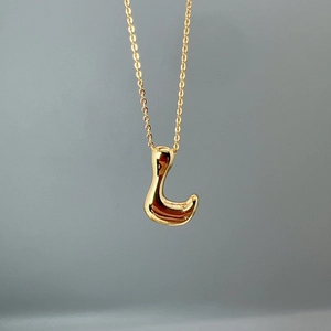 Detailed close-up of a polished gold-plated initial L pendant with an elegant O-chain