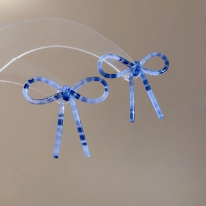 Vue macro de boucles d'oreilles nœud en acétate bleu avec motif écaille de tortue