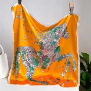 Detail of silk scarf with orange floral and horse patterns near a white handbag