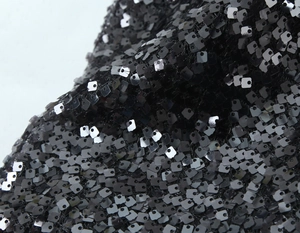 Gros plan de sequins noirs carrés sur une robe de soirée sexy aux détails scintillants