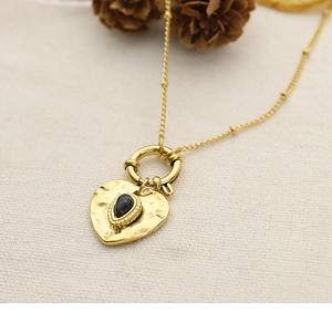 Macro detail of 18K gold plated heart pendant with hammer finish and black stone inlay