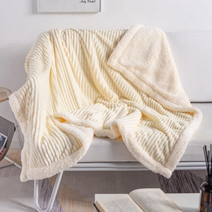Thick cream sherpa fleece blanket with textured stripes on a cozy white sofa