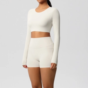 Detailopname van de crème yoga set met top met lange mouwen en shorts met zijzakken
