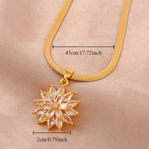 Golden snake chain necklace with crystal sunflower pendant shown on pink satin fabric