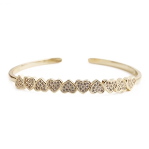 Close-up of golden open bangle featuring nine heart-shaped elements with pavé set crystals