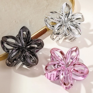 Detailed close-up of hollow plumeria flower hair claws in silver, black and pink metallic finish