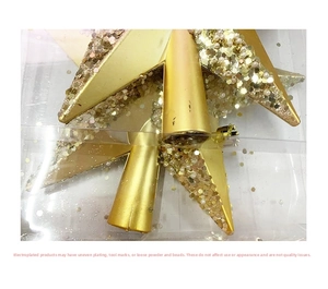 Close-up of golden star tree topper with glitter and pearls in clear packaging