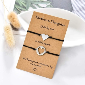 Détail de bracelets tressés mère et fille avec breloques cœur sur une carte de message