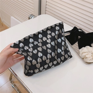 Detail of black jacquard cosmetic bag with silver heart embroidery and pleated closure