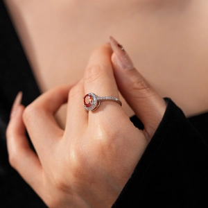 Macro detail of silver ring featuring oval orange stone and pavé zircon accents